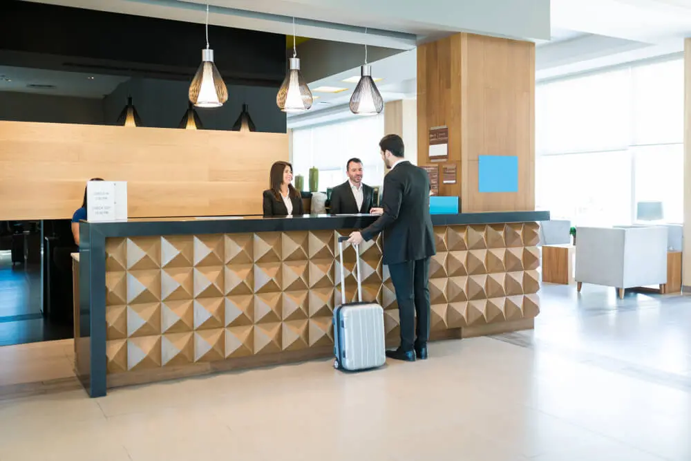 Lobby of a modern hotel with two employees at large check in desk helping a guest.